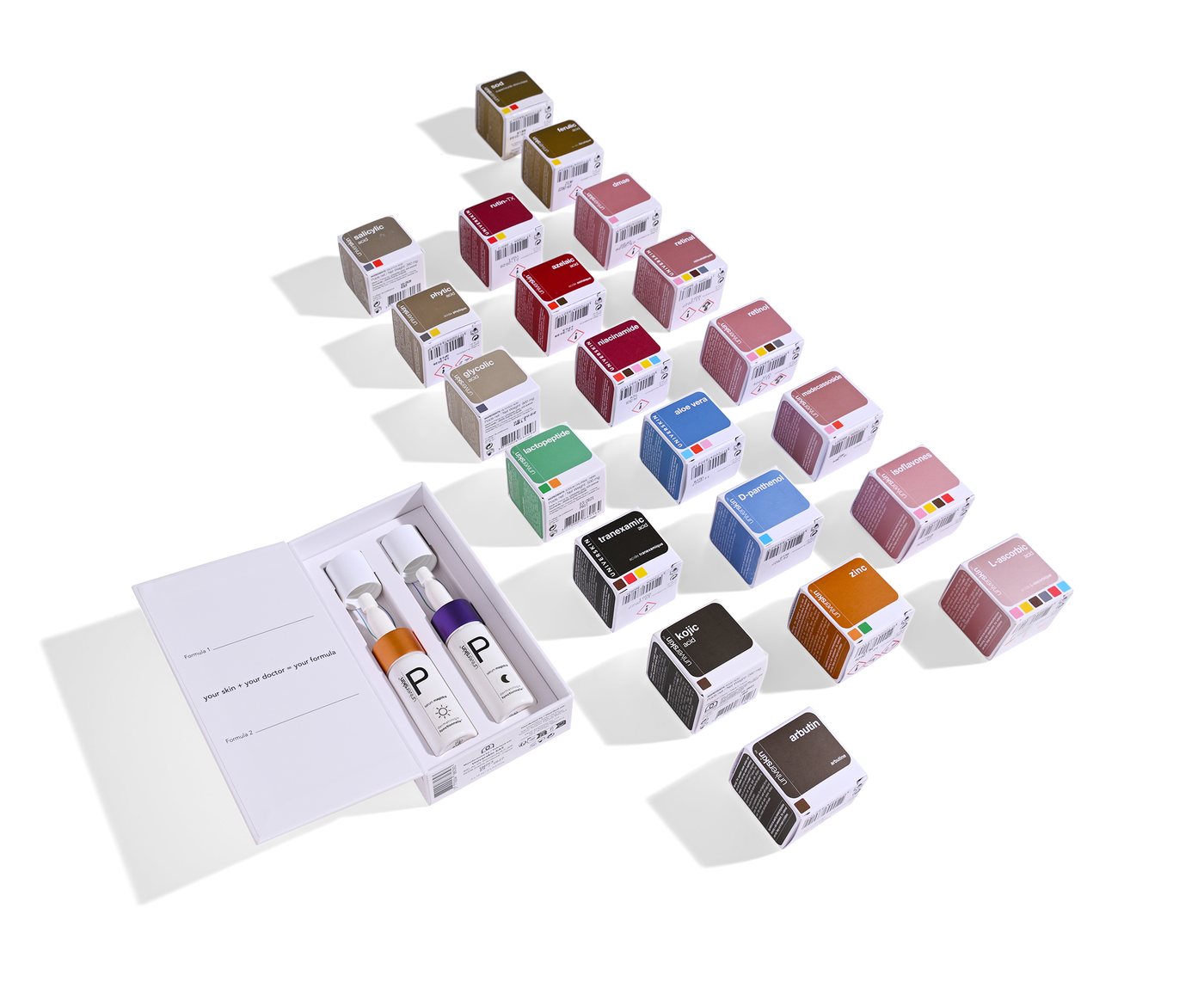 Les boîtes d’ingrédients actifs Universkin, classées par couleur, disposées à côté d’un coffret de prescription à deux formules