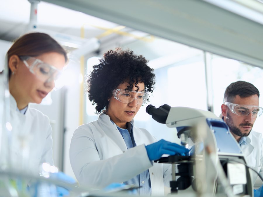 Trois scientifiques travaillant ensemble au microscope dans un laboratoire