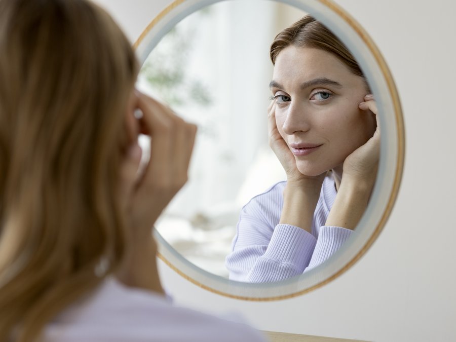 Une femme examinant sa peau de près dans un miroir rond