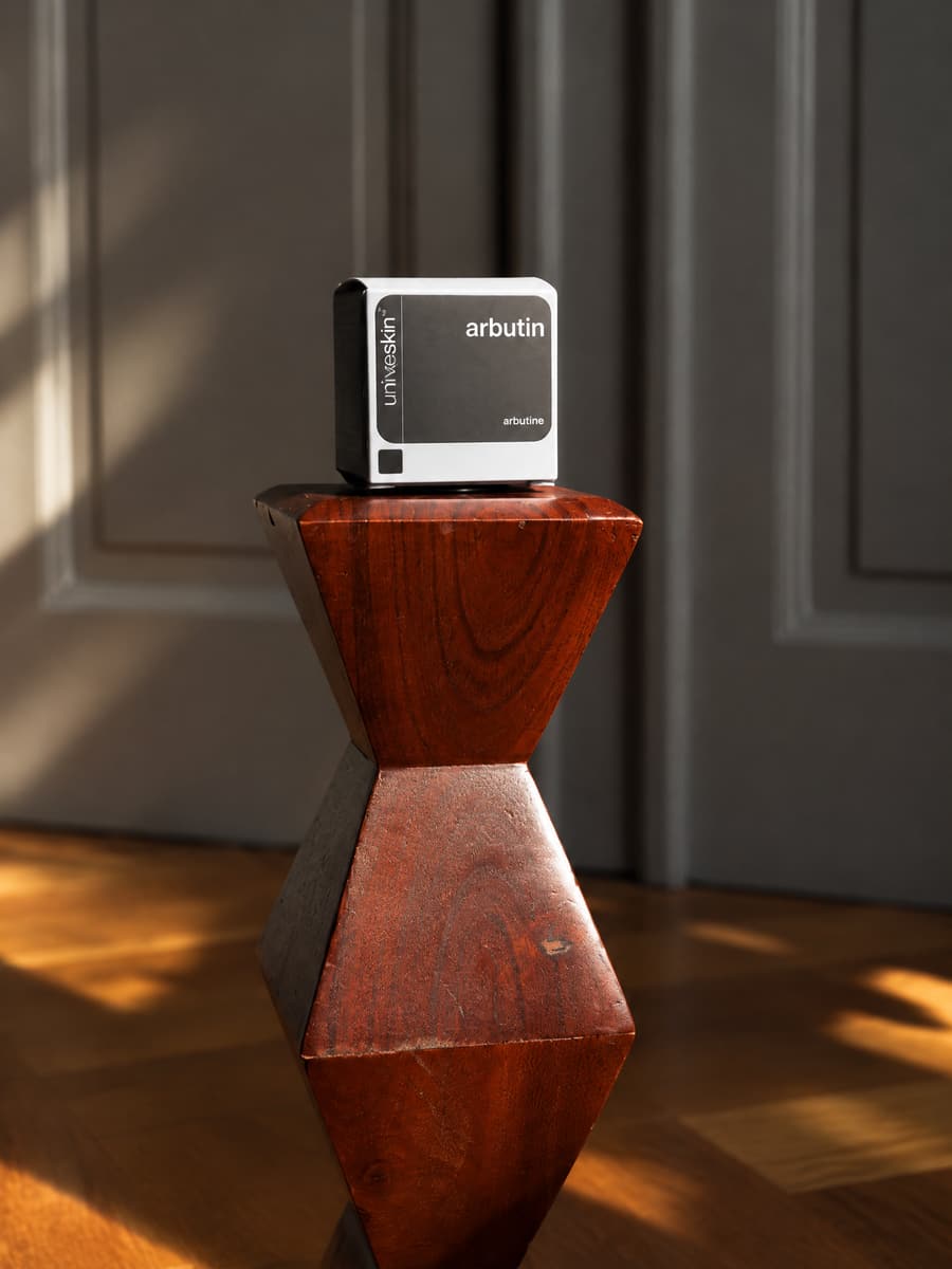 Universkin arbutin box on a carved wooden stand in warm autumn light