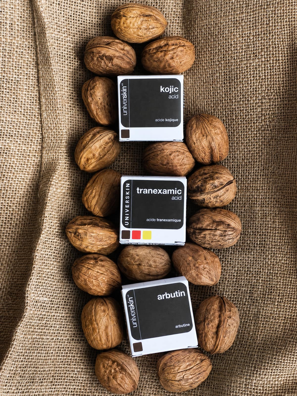 Universkin kojic acid, tranexamic acid and arbutin boxes laid on burlap among walnuts