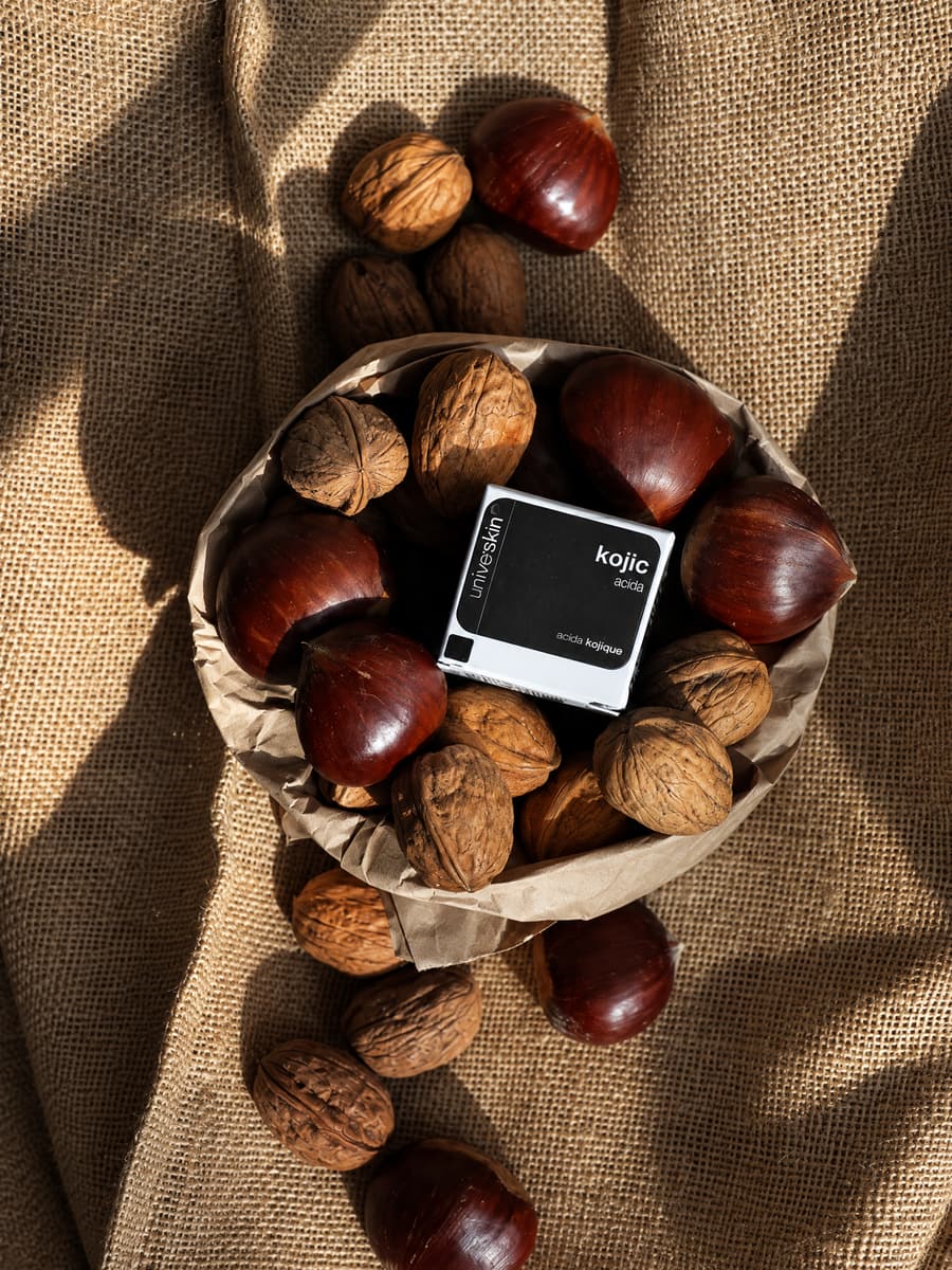 Universkin kojic acid box in a paper bag of walnuts and chestnuts on burlap