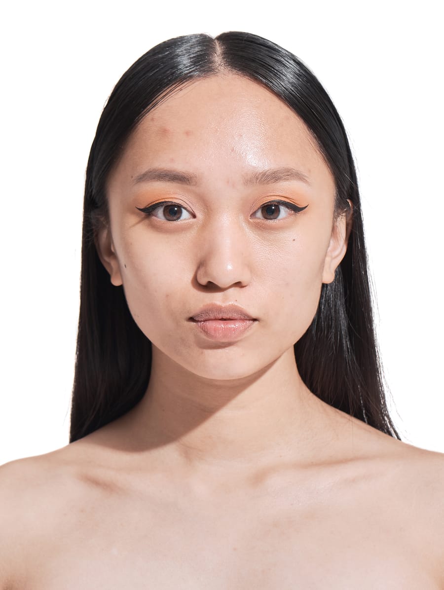 Woman with an even, luminous complexion touching her cheek