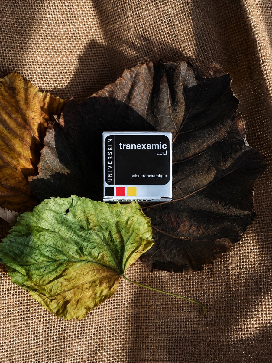 Universkin tranexamic acid box on autumn leaves laid over burlap
